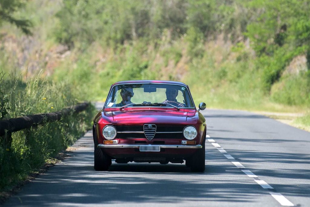 Des personnes à bord d'un véhicule de collection rouge durant un rallye en voiture ancienne dans l'Indre